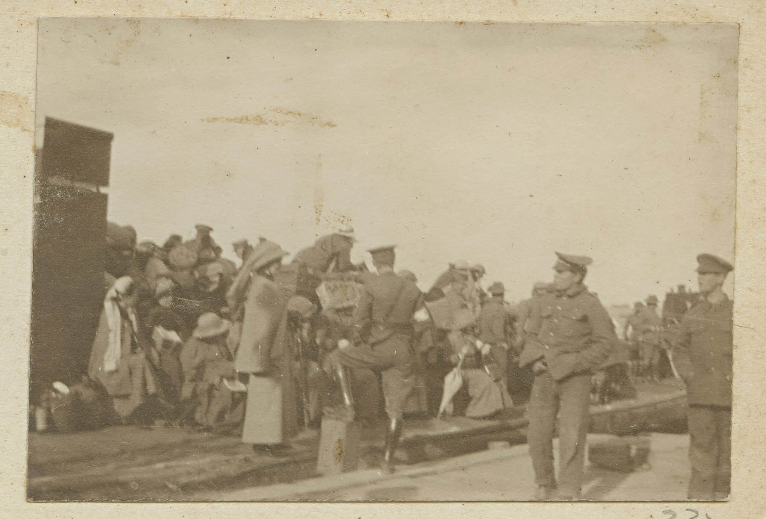 A crowd of nurses and soldiers are outside, shifting luggage or overlooking the activity.